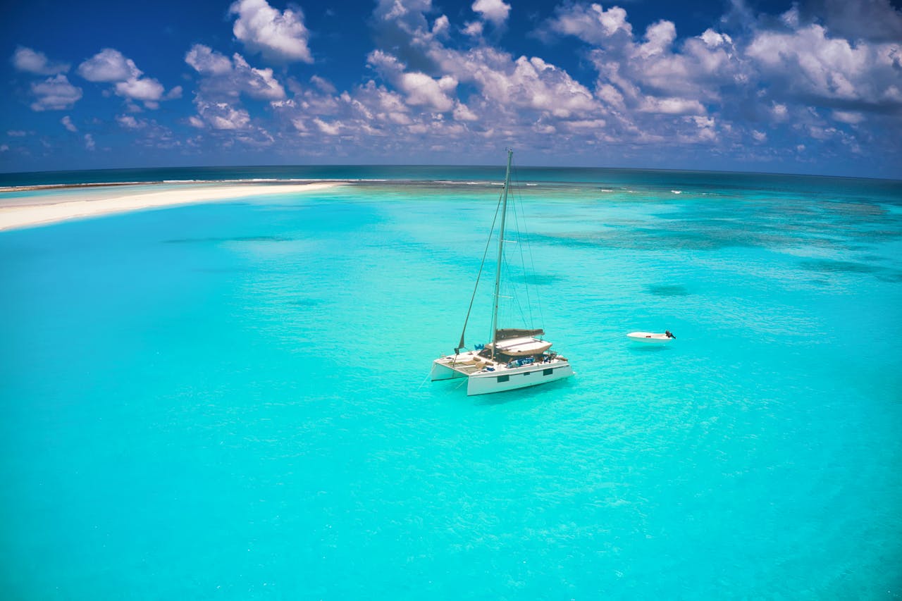 A scenic aerial shot of a sailboat and a sandbar in the turquoise waters of Mauritius.